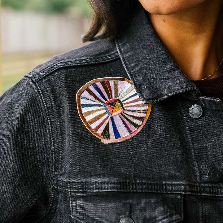 Wearing the Quilt Patches Denim Jacket—a black women's denim jacket with a large, colorful circular embroidered patch on the upper left—makes a bold statement at the Henry Ford Museum.
