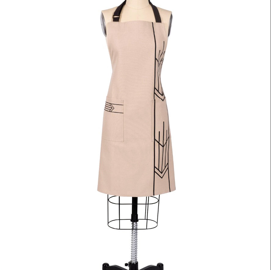 The Frank Lloyd Wright Prairie Arrow Apron is a beige designer kitchen apron with black geometric lines, a front pocket, and a black neck strap, inspired by Wright’s designs and shown on a dress form mannequin.