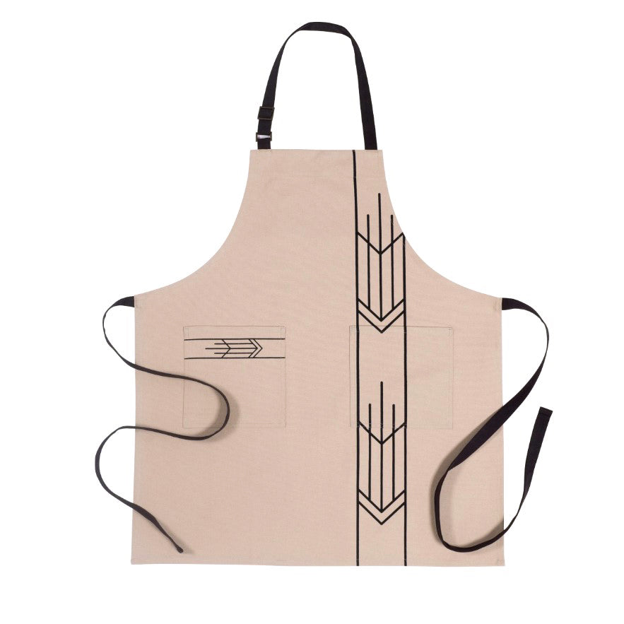 The Frank Lloyd Wright Prairie Arrow Apron is a beige cotton designer apron with black straps, geometric black line designs, and two square pockets—one arrow-patterned and one plain—shown flat on a white background.