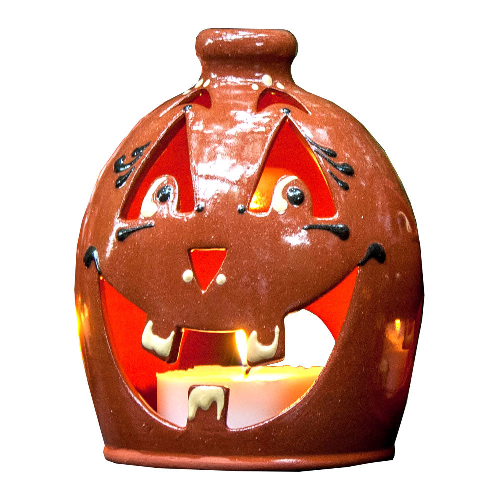 The Small Handcrafted Luminary Pumpkin features a carved, smiling face and painted details with a glossy brownish-orange finish. It holds a lit tealight candle inside, casting a cozy, warm glow.