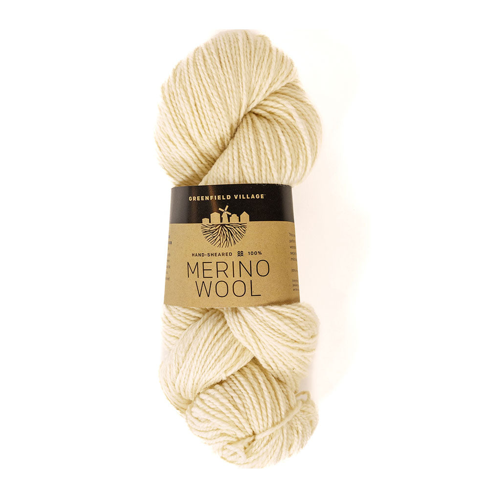 A skein of Greenfield Village 100% Merino Wool Yarn, cream-colored and soft, features a brown label reading “Greenfield Village Merino Wool, Hand-Sheared, 100%.” Ideal for knitting or crocheting.
