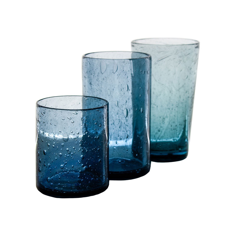 Three hand-crafted Recycled Tumblers of varying heights and shapes, each with blue tint, textured bubbles, and a slightly irregular surface, are arranged in a row on a white background.