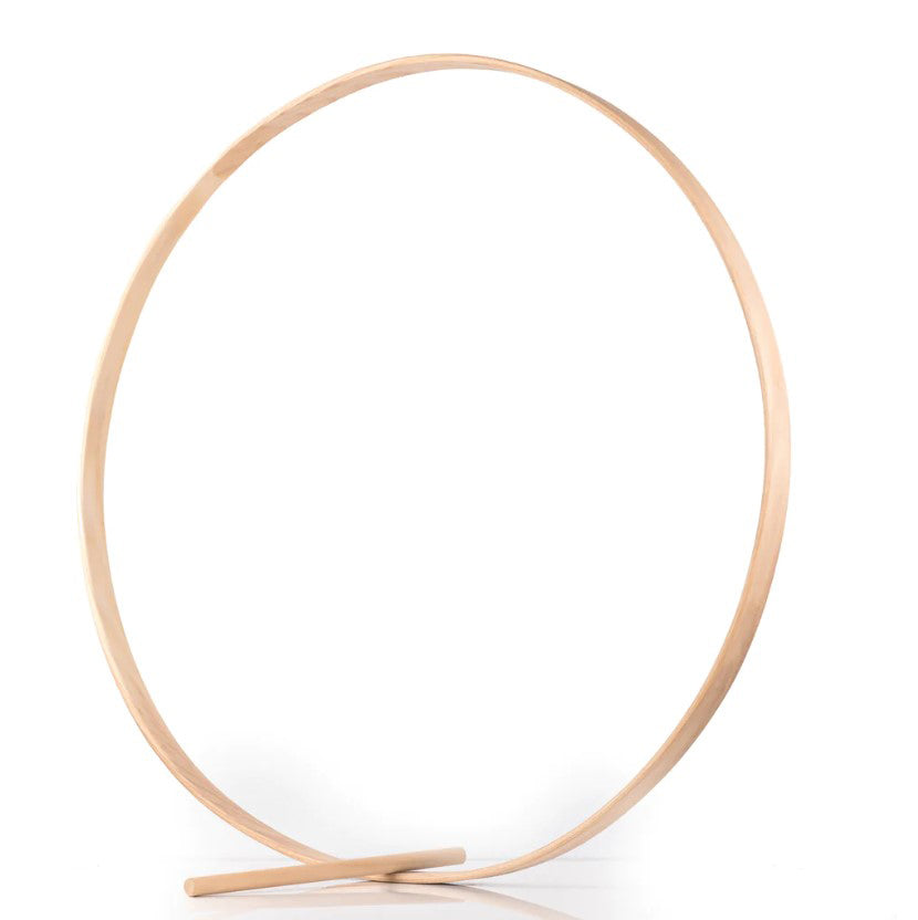 The Rolling Hoop and Stick features a large, thin wooden ring standing upright on a flat surface, supported at its base by a short horizontal wooden bar. The background is plain white.