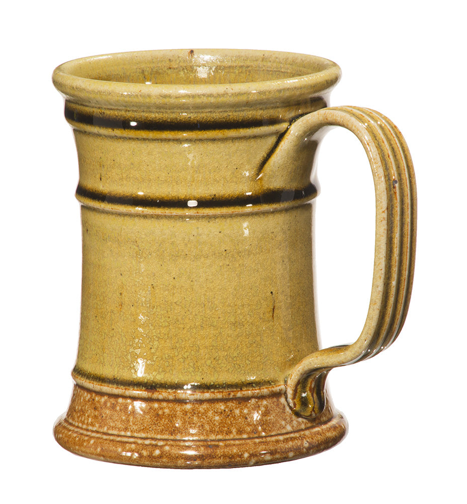 The Stoneware Tavern Tankard is a hand-thrown stoneware mug with straight sides, a wide base, ribbed handle, and light brown glaze with darker brown accents.
