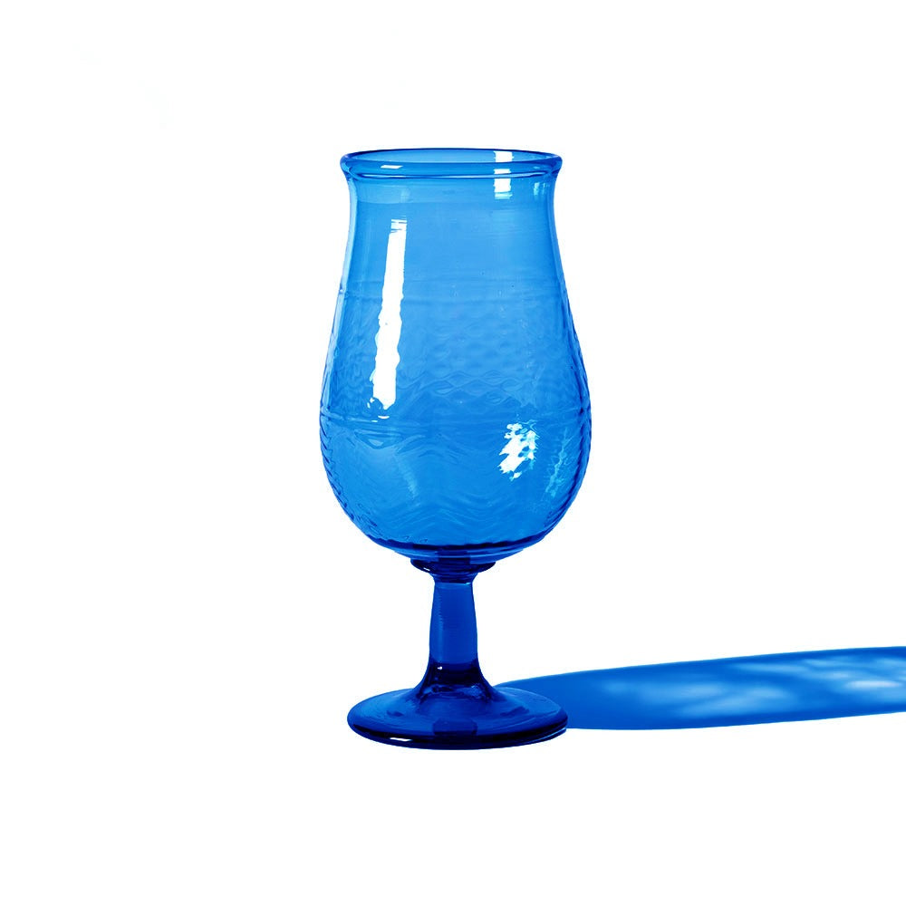 The American Heritage Molded Tulip Glass in steel blue features a textured pattern and stands on a white surface, casting a blue shadow to the right.