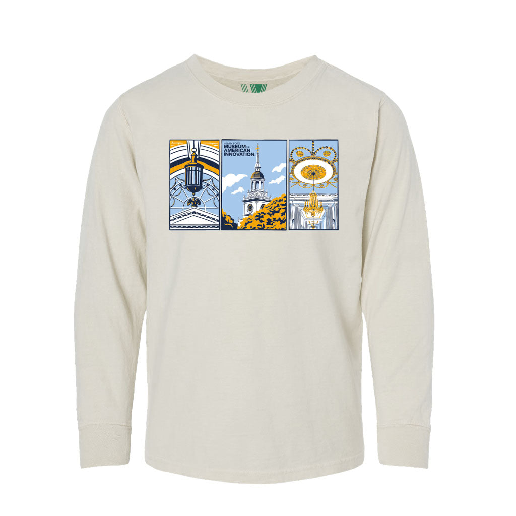 A cream-colored youth long-sleeve t-shirt featuring three illustrated panels on the chest in blue, yellow, black, and white. The center panel shows The Henry Ford Museum Building and the words "The Henry Ford Museum.